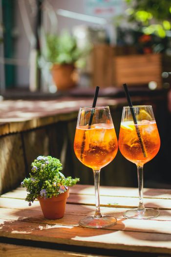 Auch in Kräuterschnaps sind Bitterstoffe: zwei Gläser mit Aperol auf einem Holztisch